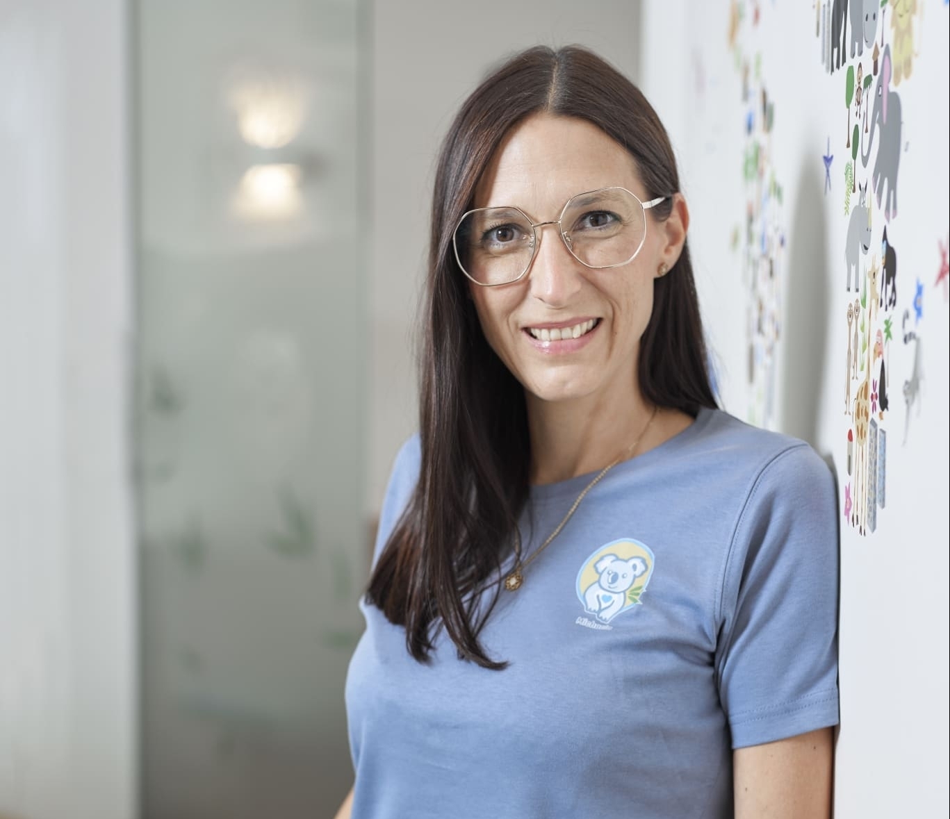 Ordinationsmanagerin Michaela Rodler, MA mit blauem Koalashirt vor Weltkarte
